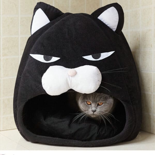 Cat inside a black cat shaped bed.