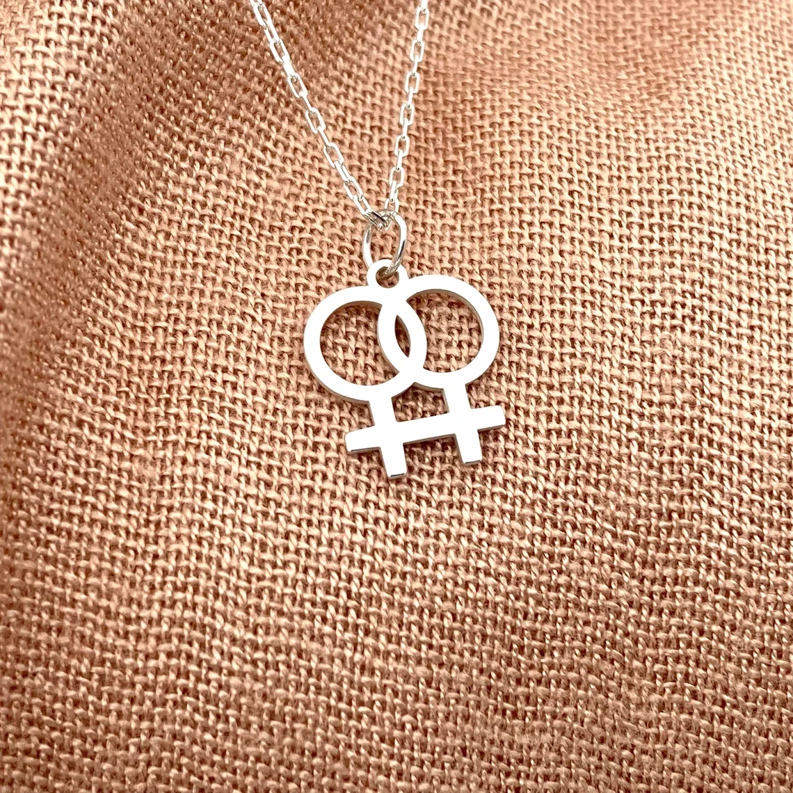 Silver lesbian symbol necklace on fabric.