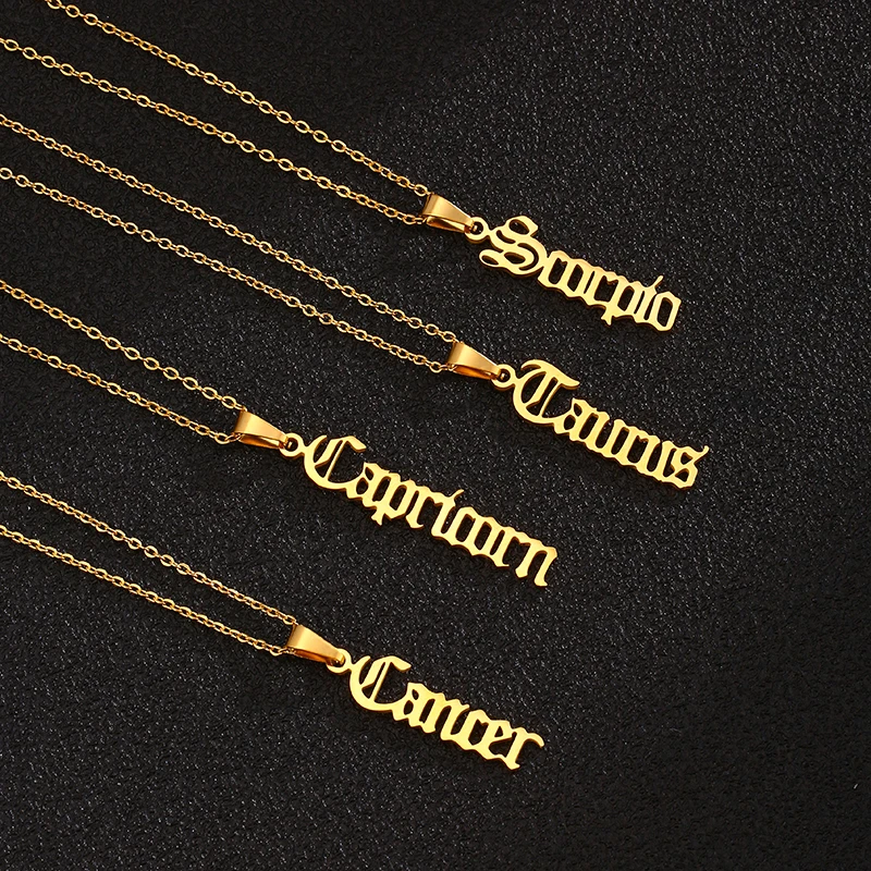 Gold zodiac sign necklaces on black background.