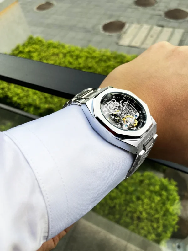 Silver skeleton watch on a wrist.