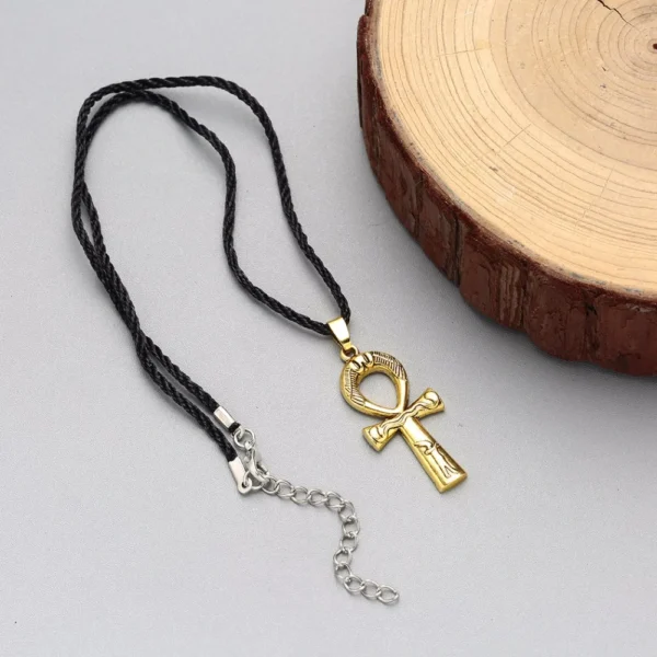 Gold ankh pendant on black cord necklace.