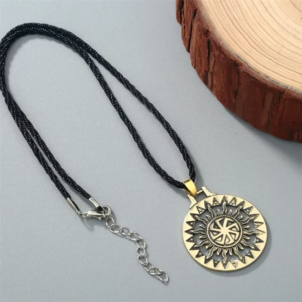 Gold sun symbol pendant necklace on black cord.