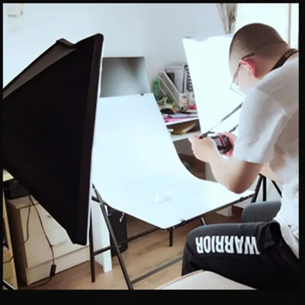 A person photographing a white backdrop.