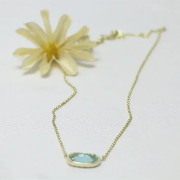 Gold chain necklace with blue gemstone pendant.