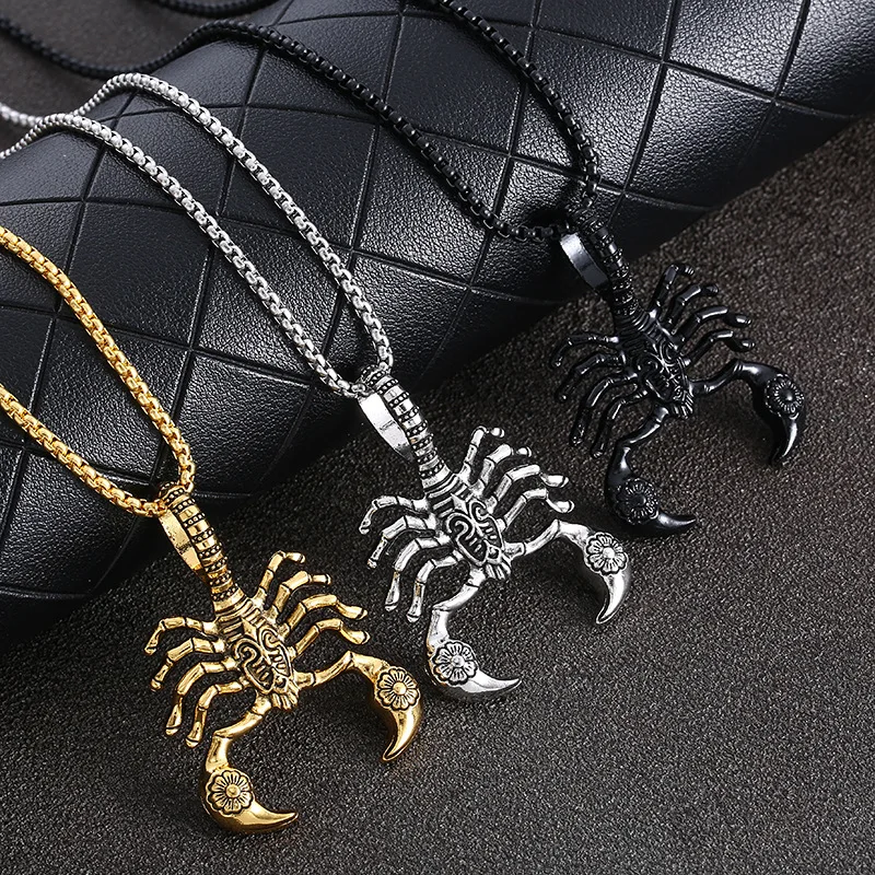 Three silver scorpion necklaces on black fabric.