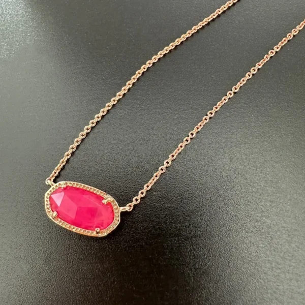 Gold chain necklace with pink gemstone pendant.