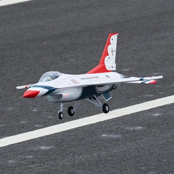 White and red fighter jet on tarmac.