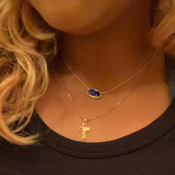 Gold necklace with blue gem and cross pendant.