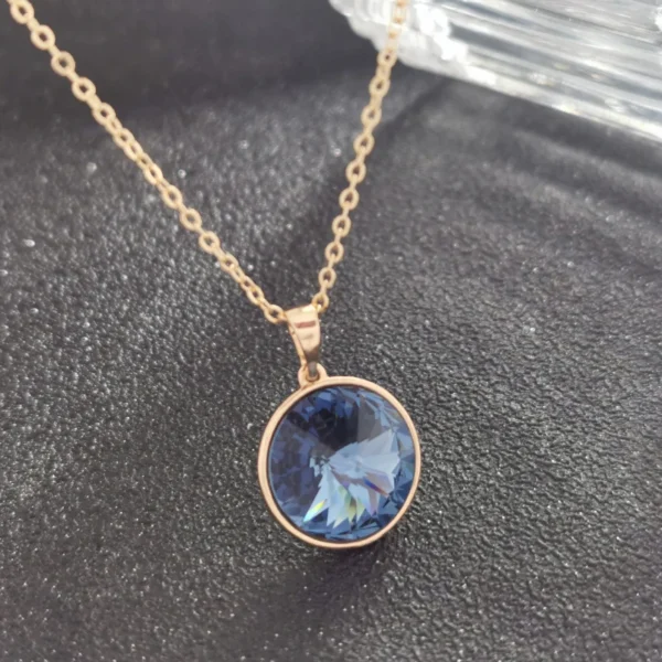 Gold necklace with blue gemstone pendant.