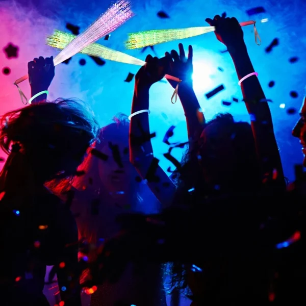 People dancing with glowing wands at a party.