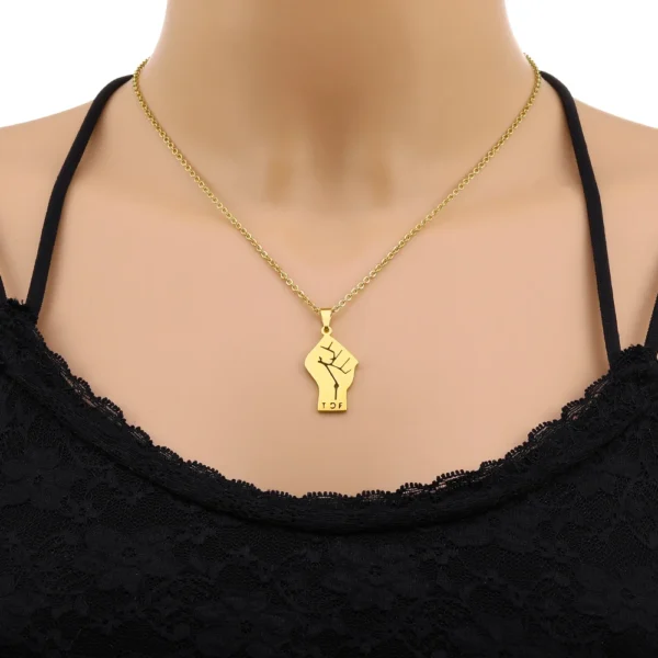 Gold necklace with raised fist pendant.