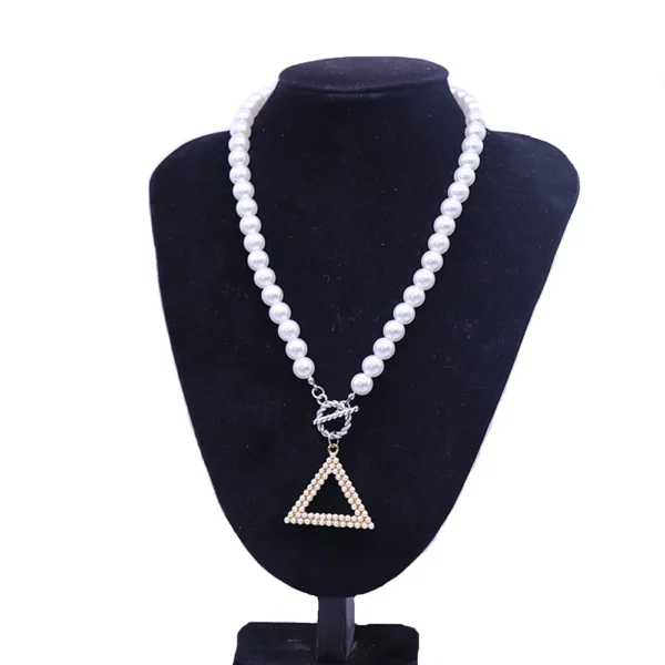 White pearl necklace with triangle pendant.