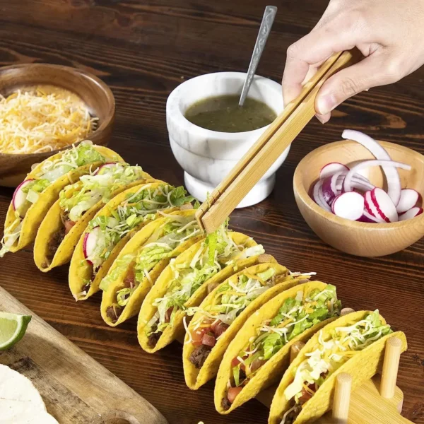 Hand holding chopsticks over tacos on stand.