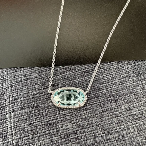 Silver chain necklace with blue gemstone pendant.