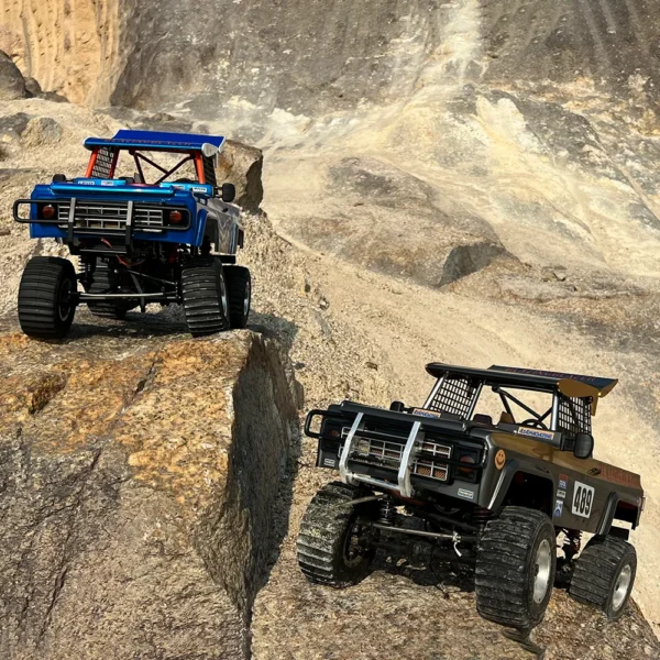 Two toy off-road trucks on rocks.