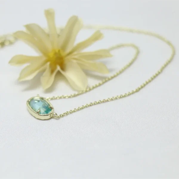 Gold chain necklace with blue gemstone pendant.