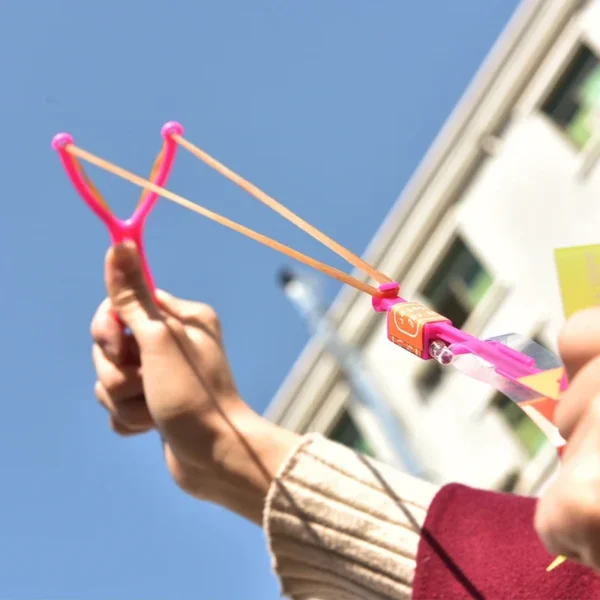 Person holding pink slingshot with rubber bands.