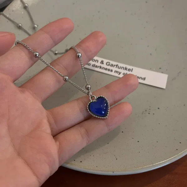 Silver chain necklace with blue heart pendant.