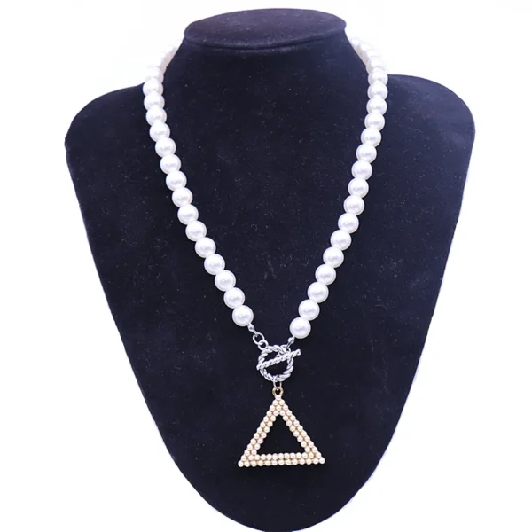 White pearl necklace with triangle pendant.