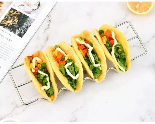 Four filled taco shells on a wire rack.