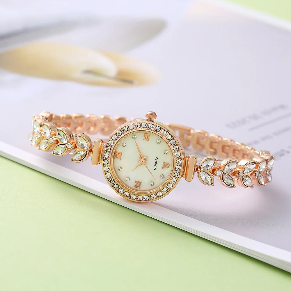 Gold wristwatch with leaf detail and crystals.