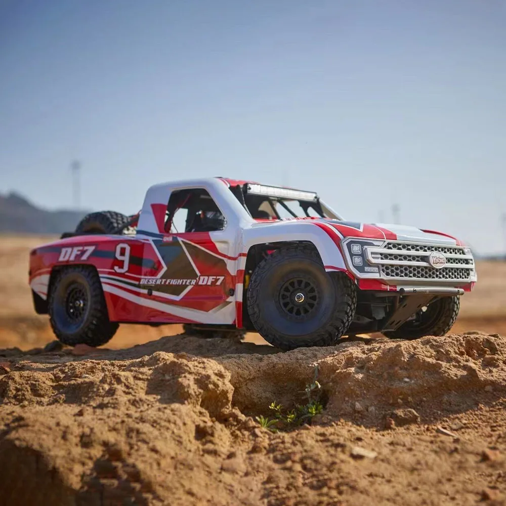 White and red off-road truck on sand.