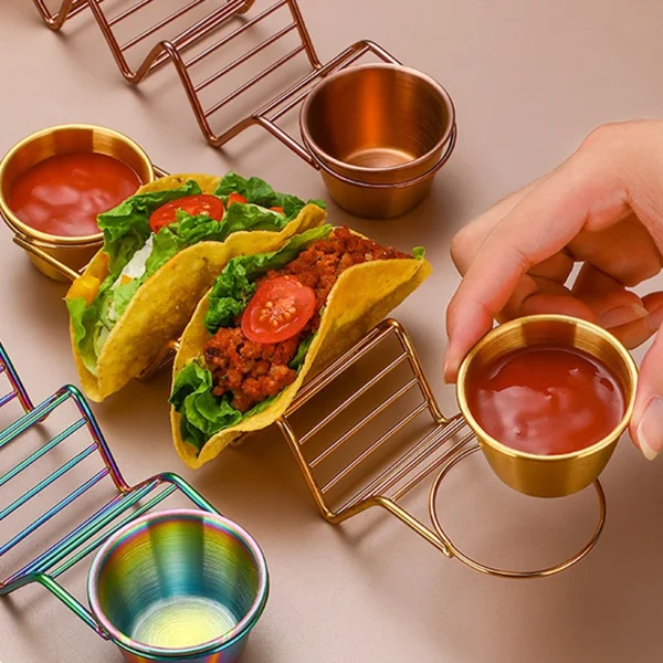 Two tacos with dipping sauce on a metal stand.