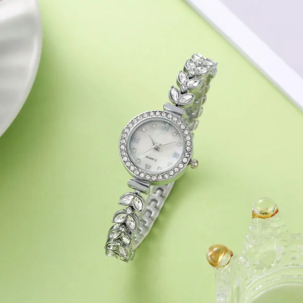 Silver watch with crystal accents and a white face.