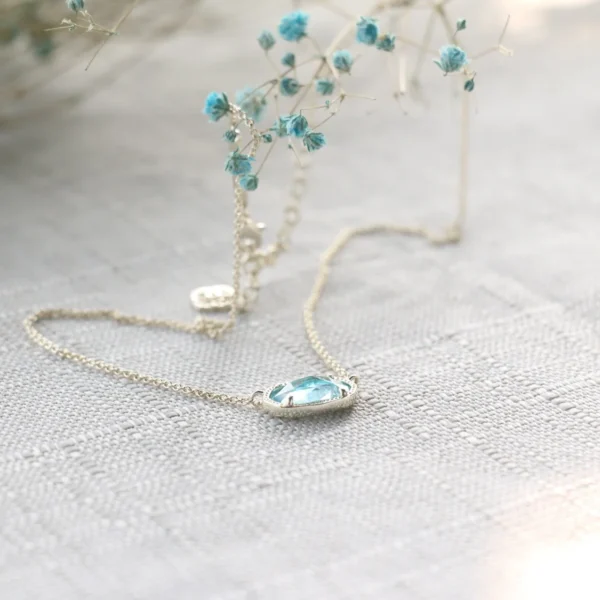 Silver necklace with blue gemstone pendant.