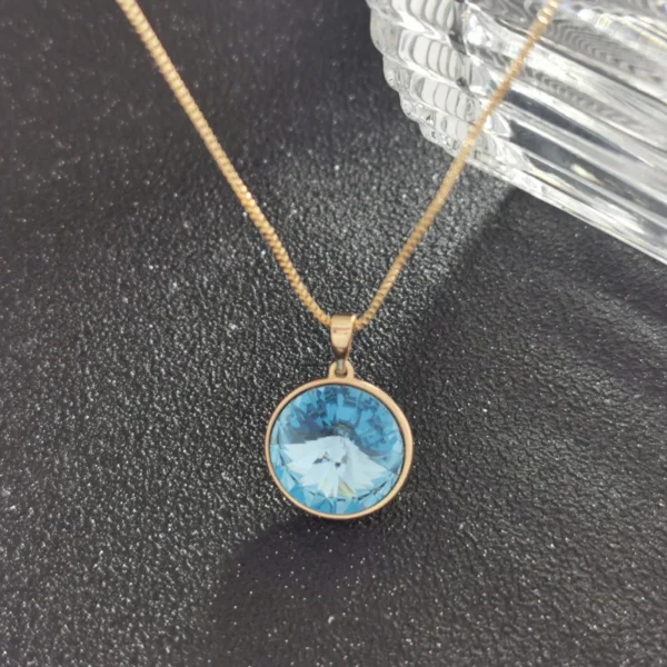 Gold chain with blue gemstone pendant.